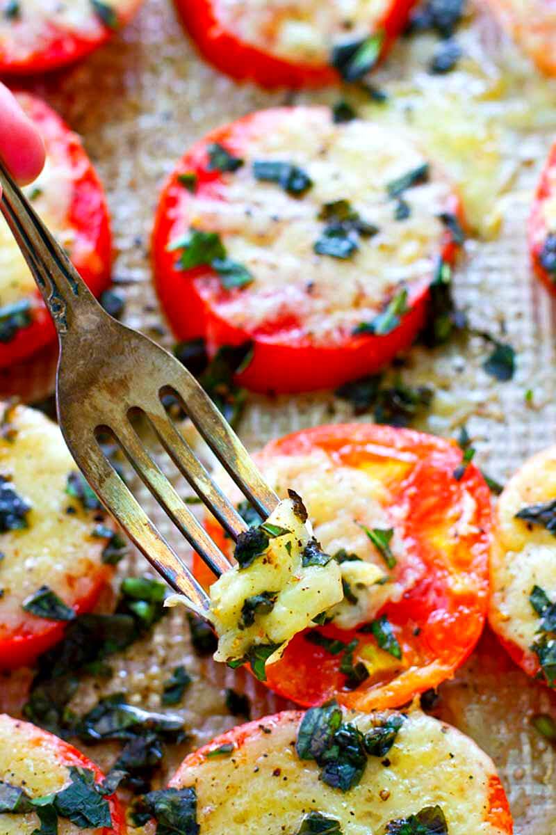 These Baked Parmesan Basil Heirloom Tomatoes are covered in TONS of gooey cheese and fresh basil for one super-simple AND healthier summer side dish! You won't be able to resist eating them straight off the sheet.