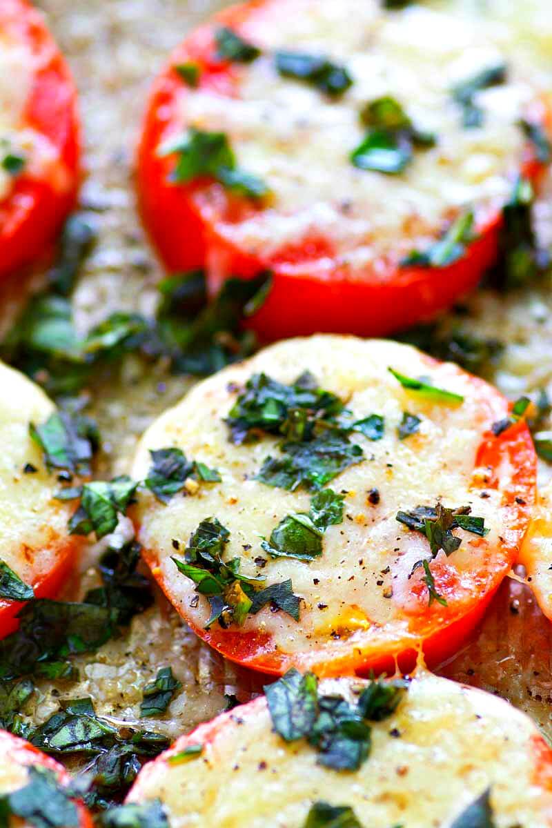 These Baked Parmesan Basil Heirloom Tomatoes are covered in TONS of gooey cheese and fresh basil for one super-simple AND healthier summer side dish! You won't be able to resist eating them straight off the sheet.