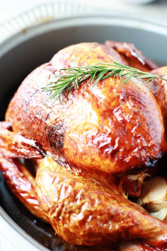Juicy tender roasted turkey in roasting pan with rosemary for garnish