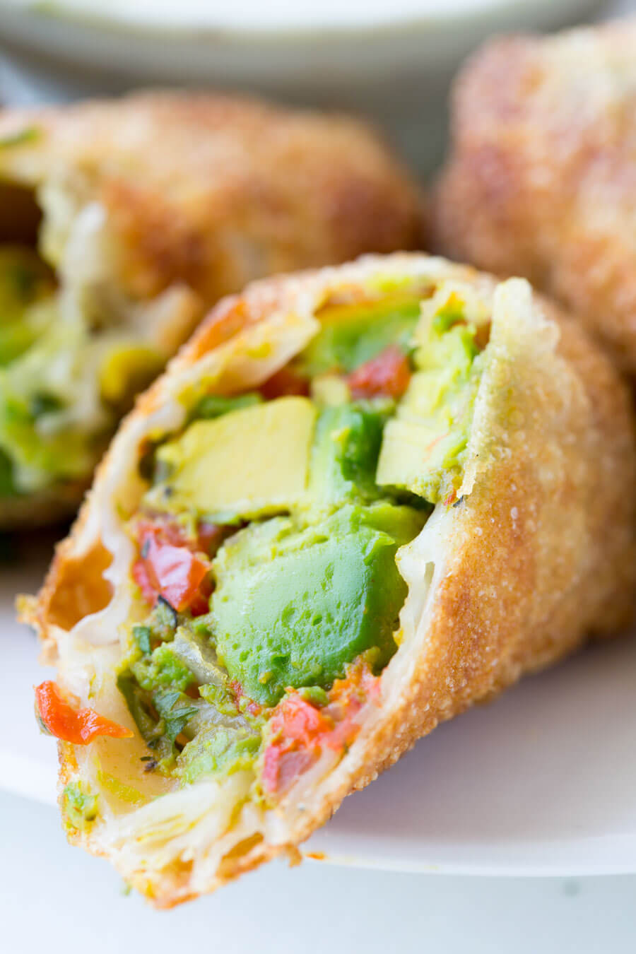 Avocado Egg Rolls: Crunchy egg roll wrapper filled with chunks of California Avocados, cilantro, tomatoes, red onion, and roasted red peppers; dipped in a creamy avocado ranch dipping sauce!