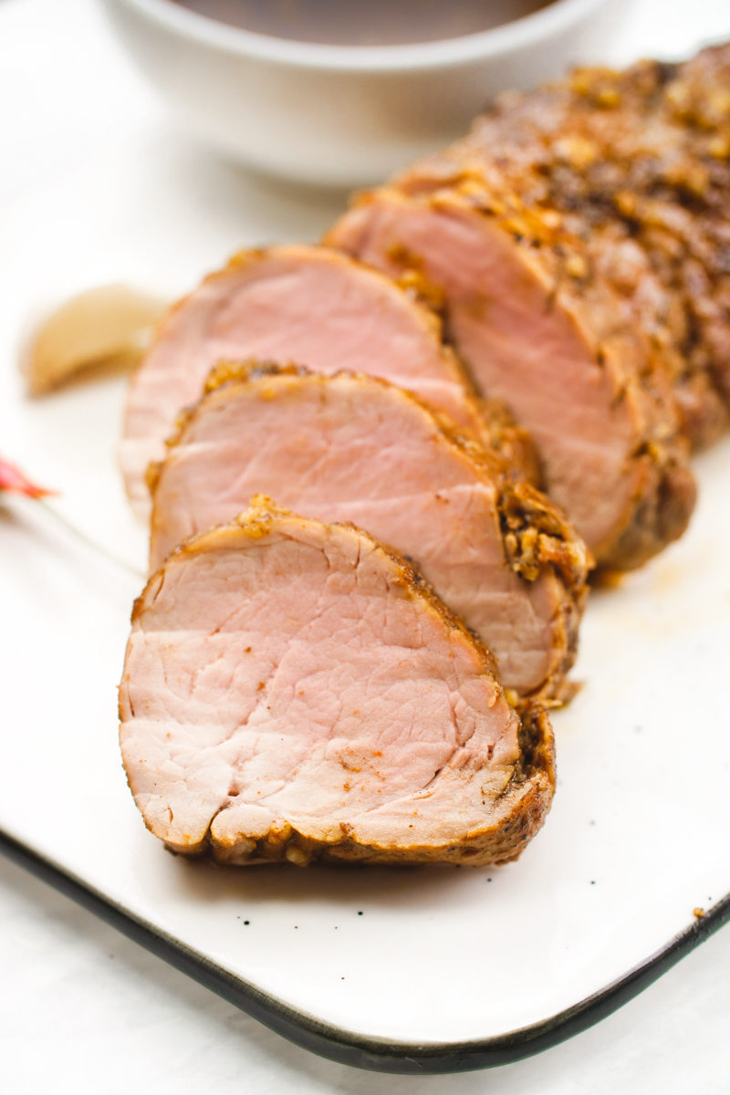A tender, perfectly cooked pork tenderloin baked then placed on a white platter