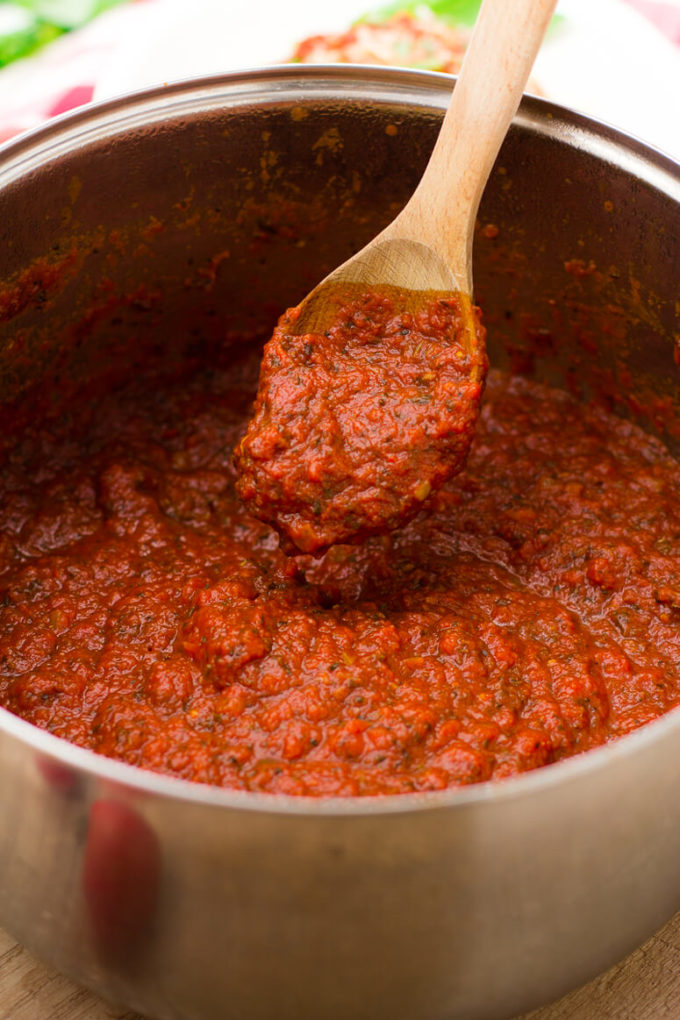 Easy homemade spaghetti sauce being scooped out of a silver pot by a wooden spoon