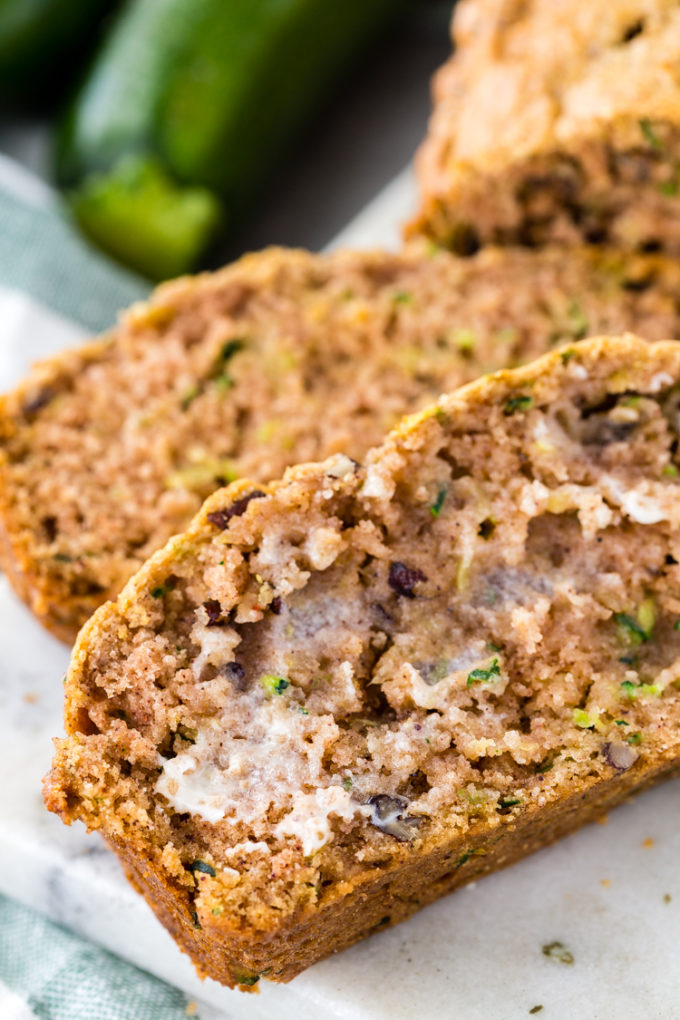 A slice of easy zucchini bread slathered in butter and served while still warm