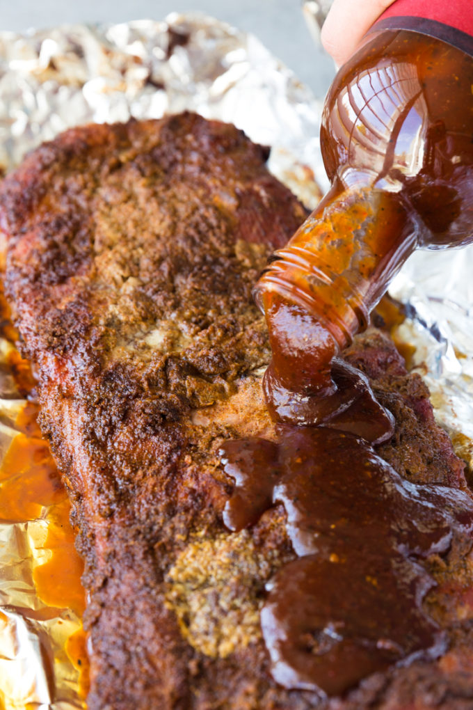 Pouring BBQ sauce on Baby back ribs