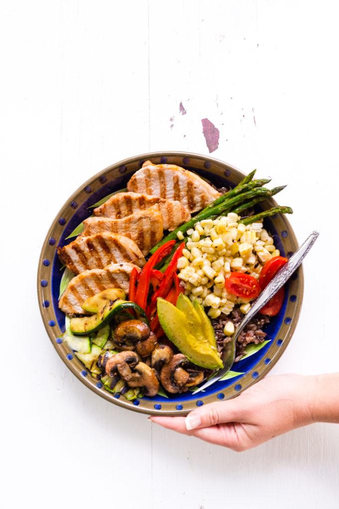 Grilled pork power bowl with grilled pork medallions, asparagus, avocado, red bell pepper, corn, mushrooms, and grape tomatoes