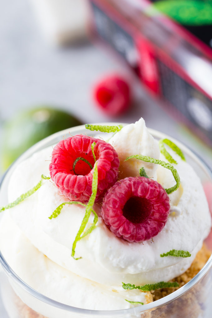 The top of a raspberry cheesecake trifle with two raspberries and lime zest