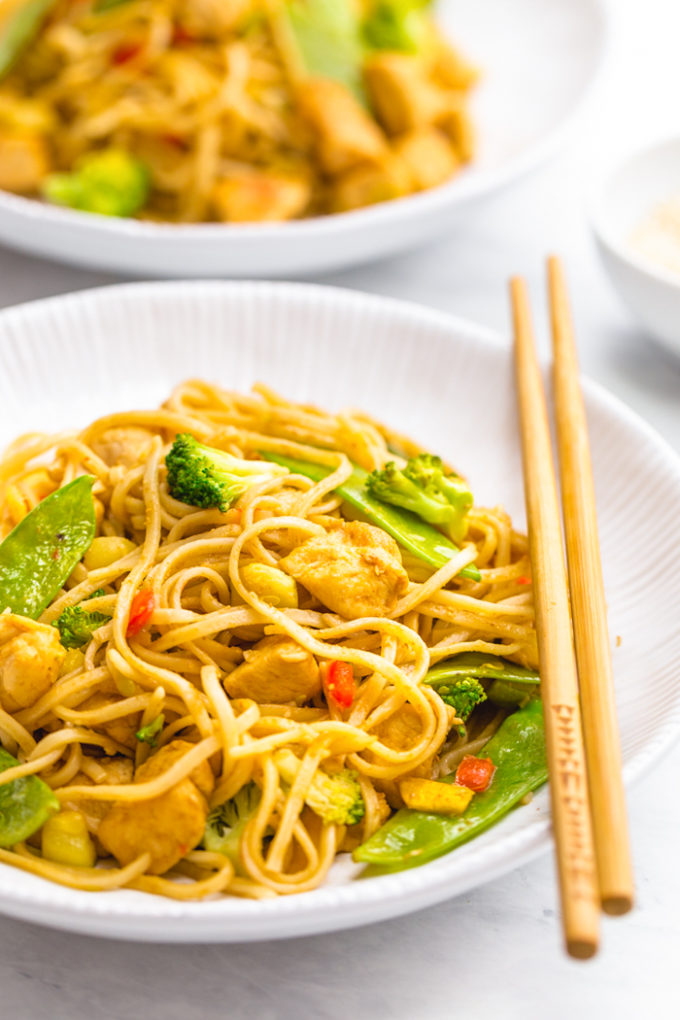 Easy garlic chicken lo mein in a white dish with chopsticks