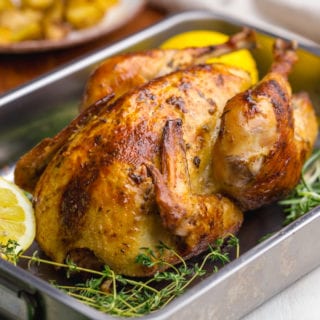 Beautifully roasted chicken, oven roast chicken in a pan with lemons and rosemary