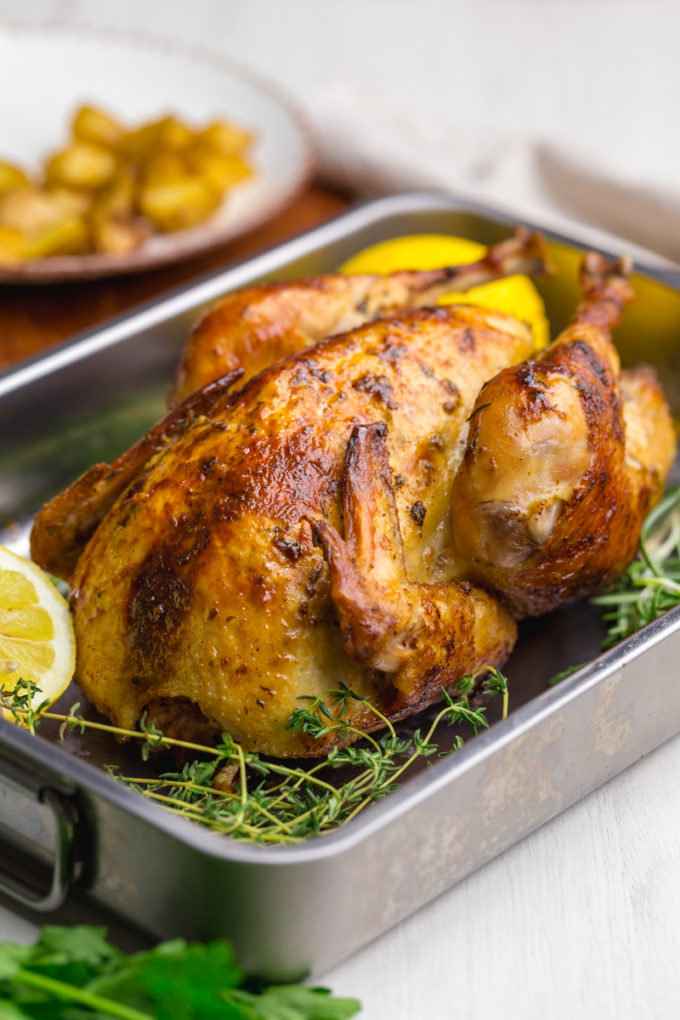 Beautifully roasted chicken, oven roast chicken in a pan with lemons and rosemary