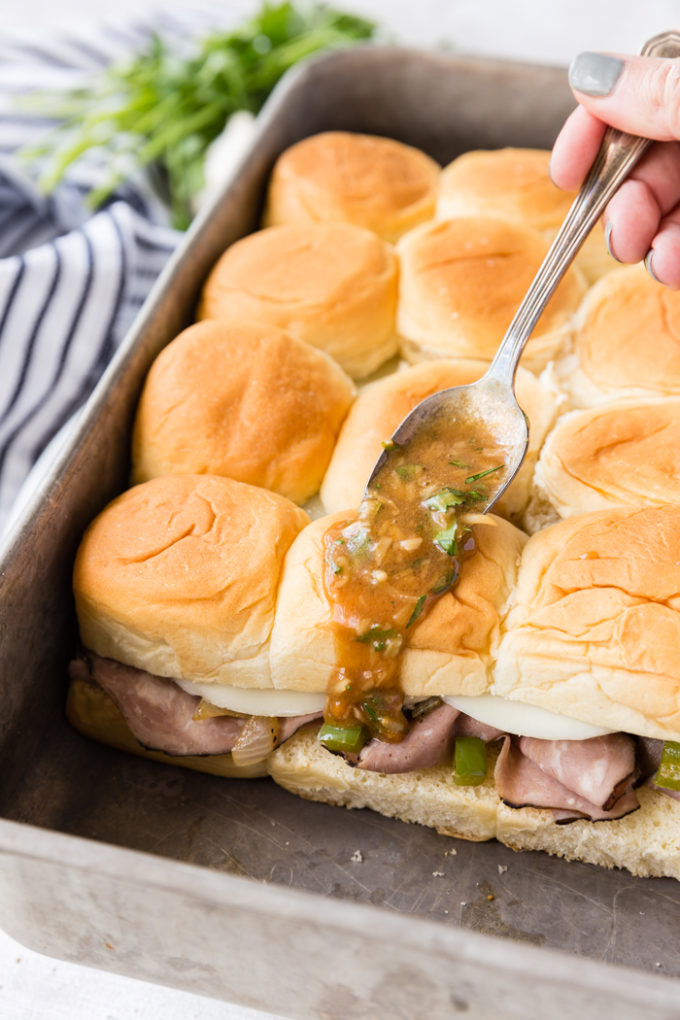 Adding the buttery herb sauce to the Philly cheese steak sliders