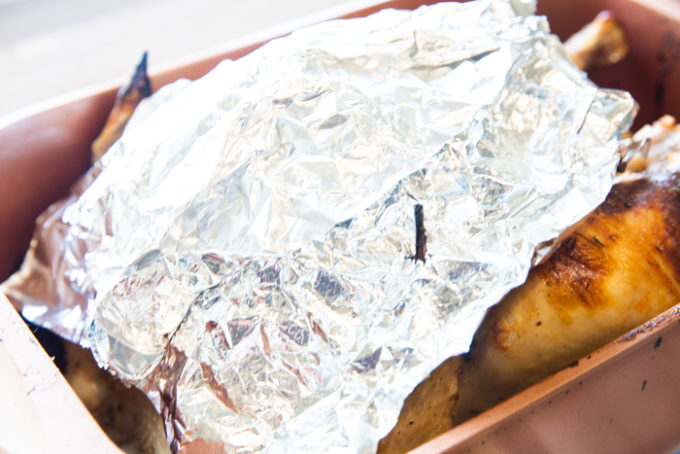 A turkey in a roasting pan with a foil hat