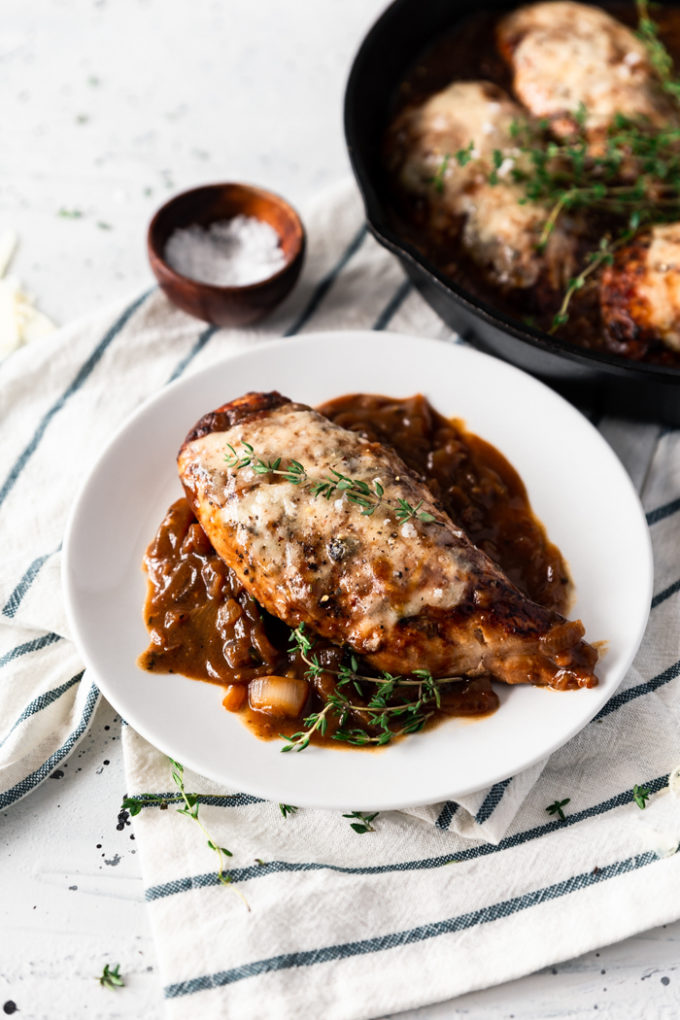 Skillet French onion chicken on a white plate, with a bit of skillet peaking in the side. 