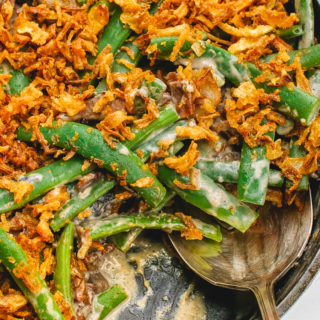 A skillet filled with green bean casserole with a spoon in it.