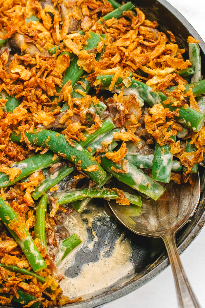 A skillet filled with green bean casserole with a spoon in it.