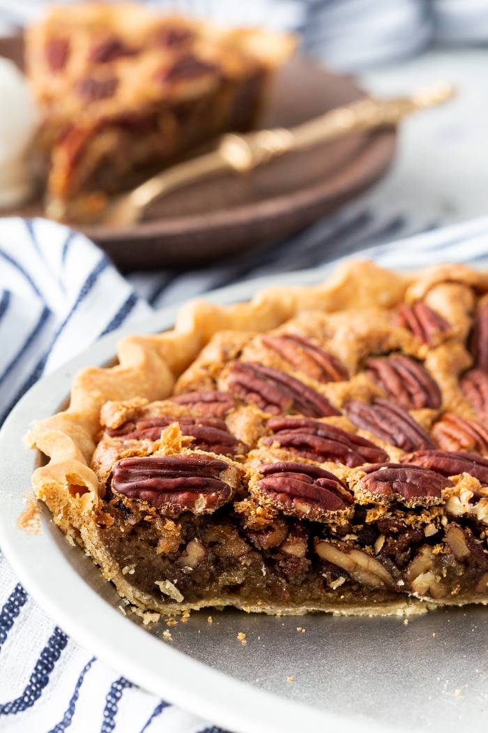 A side look at the pecan pie with a buttery, sugary filling. Crunchy pecans on top. 