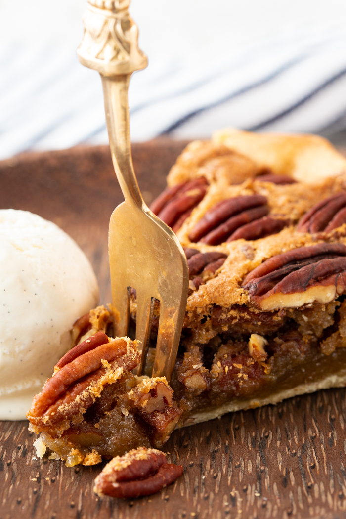 A slice of pecan pie with a fork cutting off the edge. 