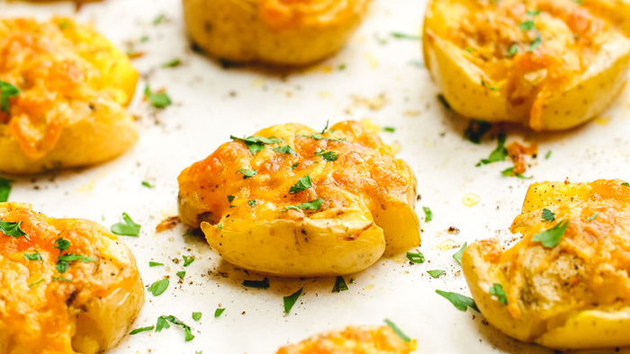 A tray of smashed Yukon gold potatoes with fresh herbs