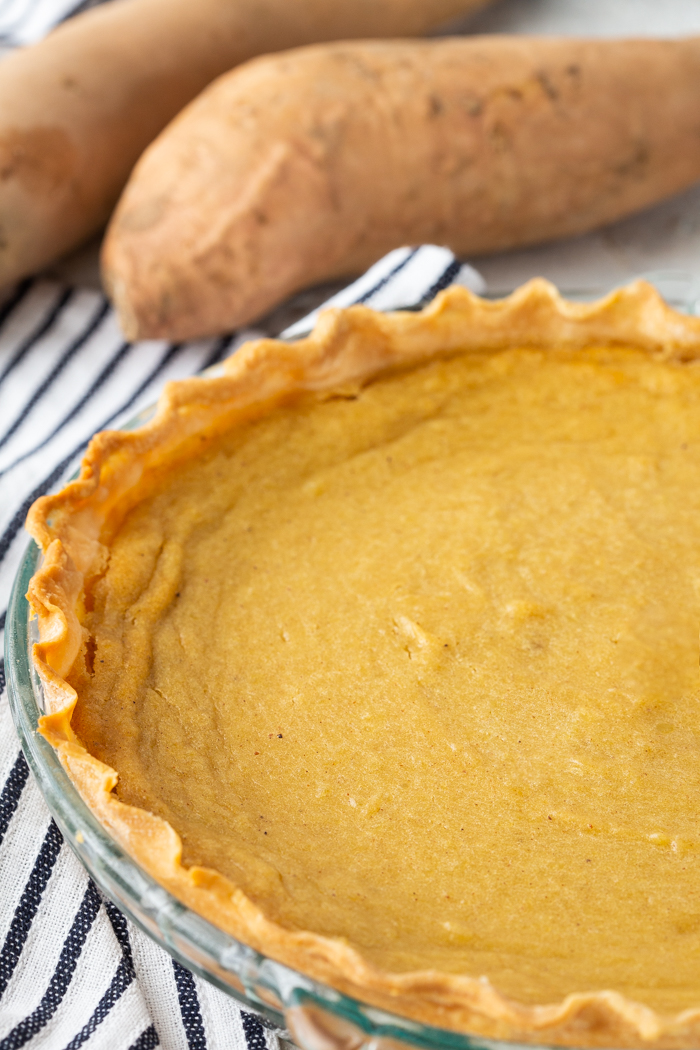 How to make a sweet potato pie. whole pie with sweet potatoes in background