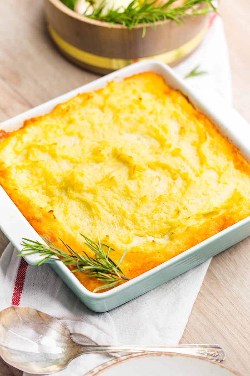 A casserole dish of shepherd's pie with mashed potatoes and rosemary on top