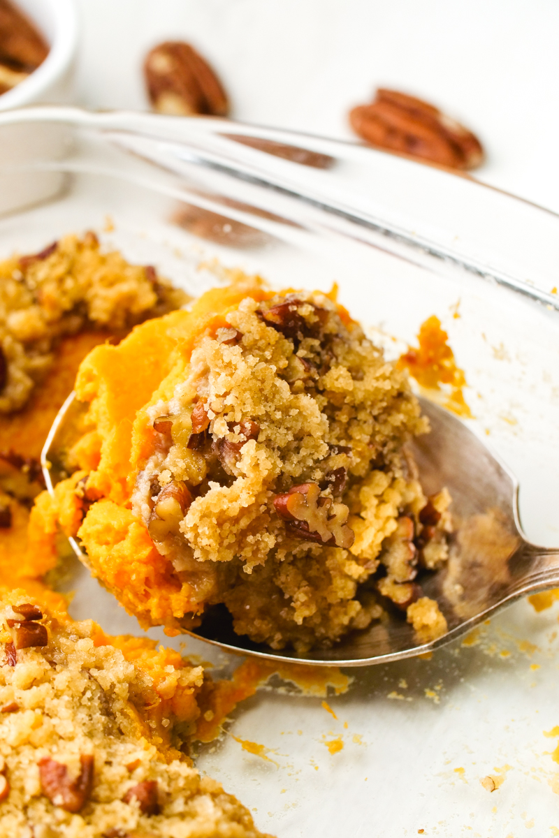 Sweet potato casserole in a spoon with a brown sugar pecan crumble topping