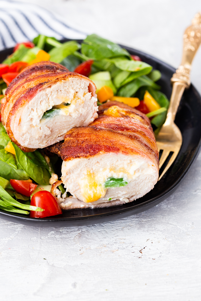 A plate of jalapeno popper stuffed chicken and spinach salad