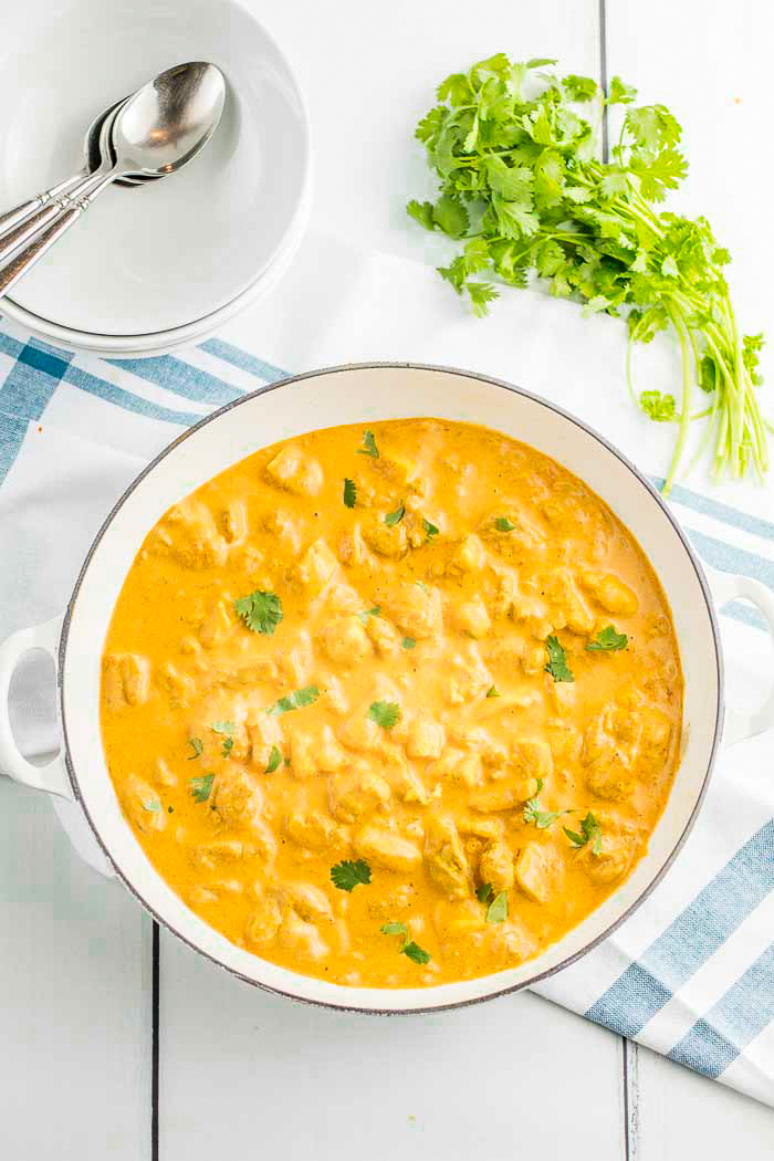 Keto Indian butter chicken recipe, low carb butter chicken in a white pot with cilantro and plates on the side