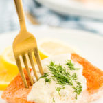 A white plate with creamy lemon dill sauce on salmon