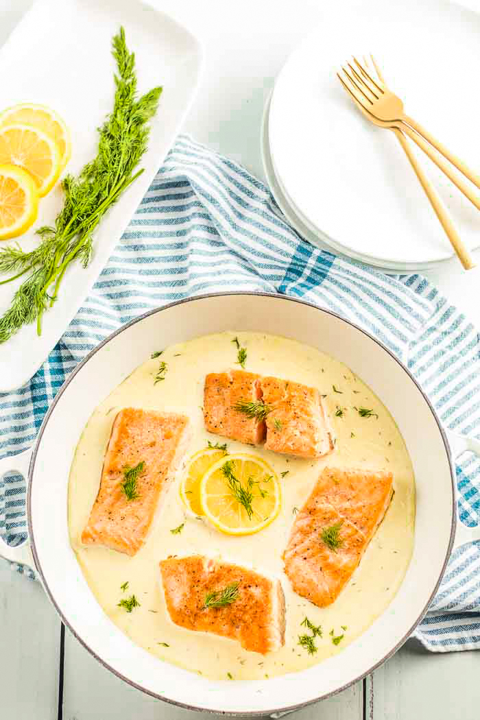 A pan full of salmon swimming in a luscious creamy lemon dill sauce