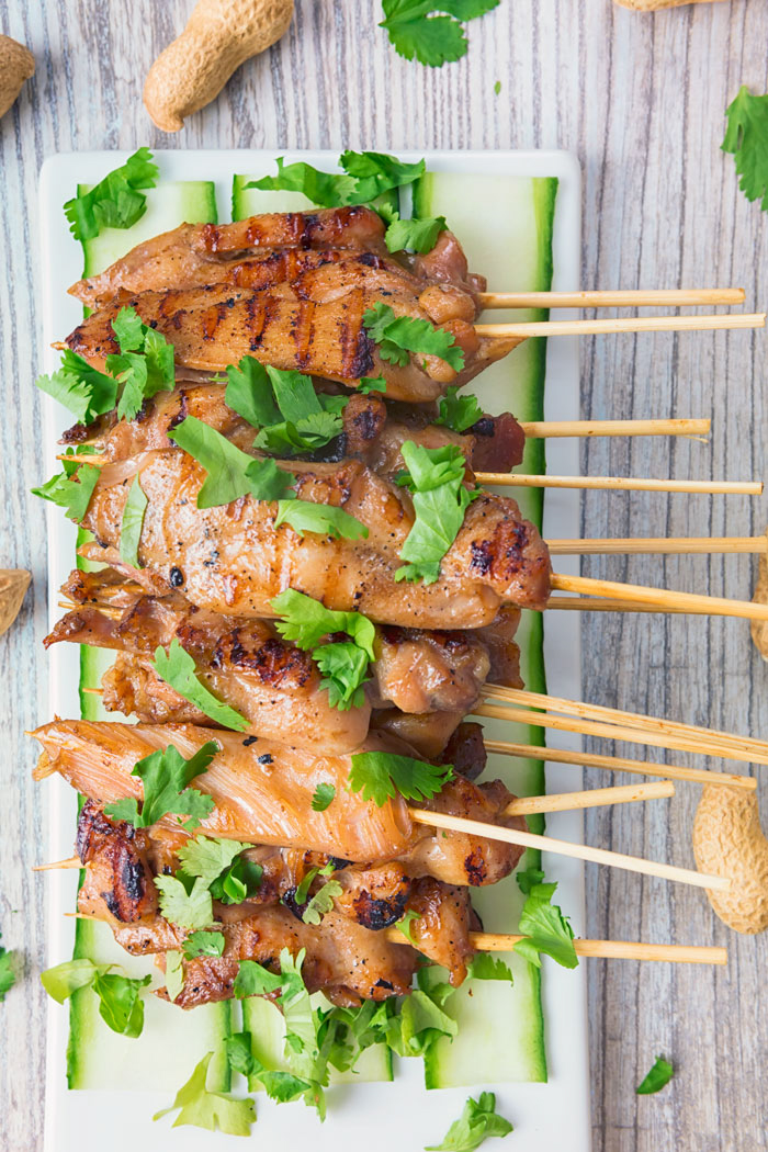 A white plate with several skewers of chicken satay