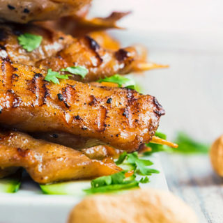 Chicken satay on a white serving plate with a peanut in front for the peanut dipping sauce