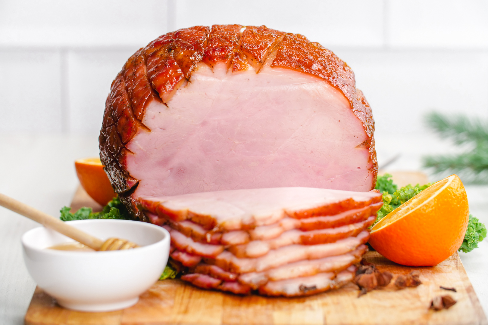 Delicious honey baked ham on a cutting board with oranges and star anise and honey