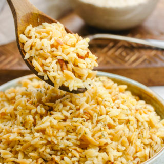 Easy to make rice pilaf in a bowl with a wooden spoon scooping some out