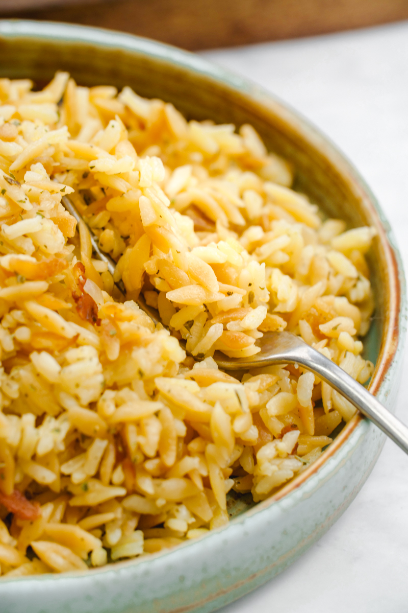 a bowl of rice pilaf being fluffed with a fork