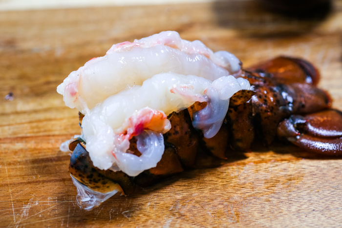 A butterflied lobster tail on a cutting board