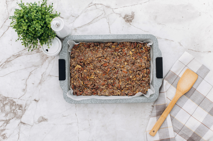 baking dish filled with keto granola and wood spatula