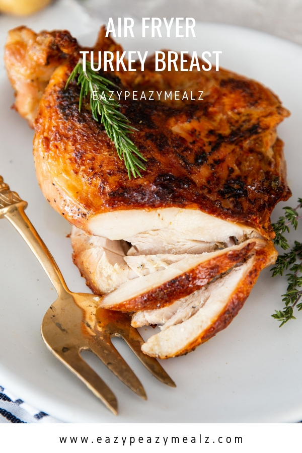 Air fryer turkey breast on a white plate, with a few slices, and a gold serving fork