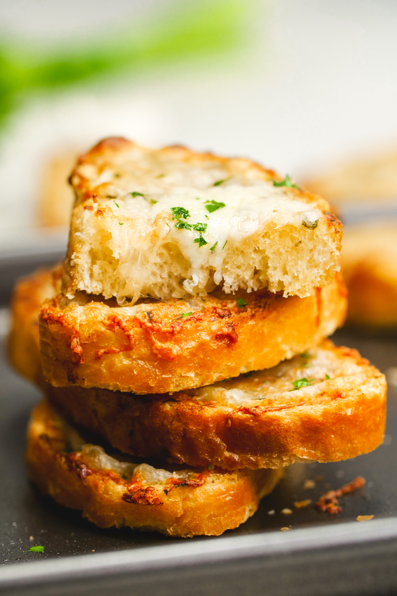 A stack of cheesy garlic bread with fresh parsley on top