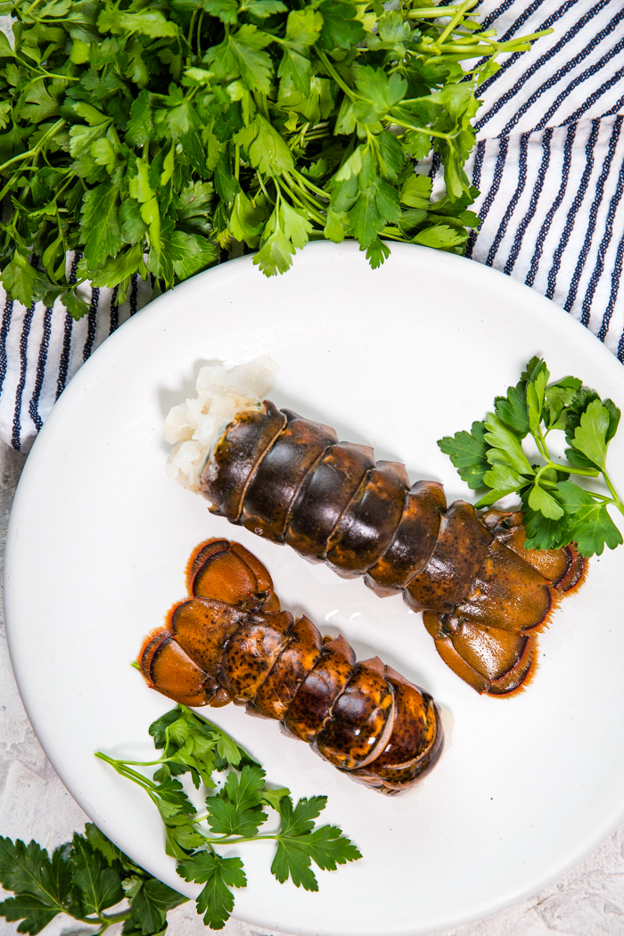 Two cold water lobster tails on a white plate. 