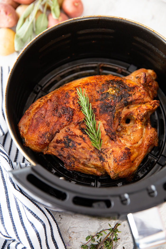 A full turkey breast cooked in the air fryer, topped with a sprig of rosemary