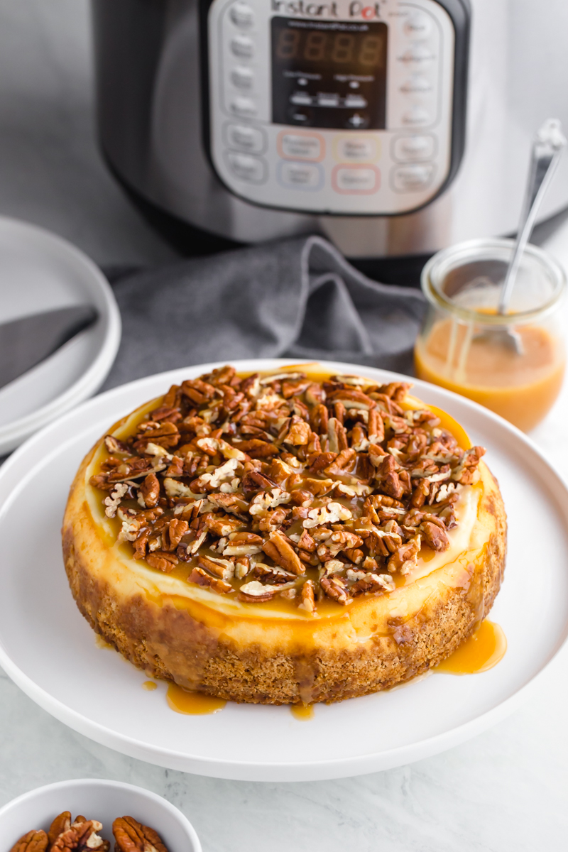 An instant pot cheesecake topped with caramel and pecans