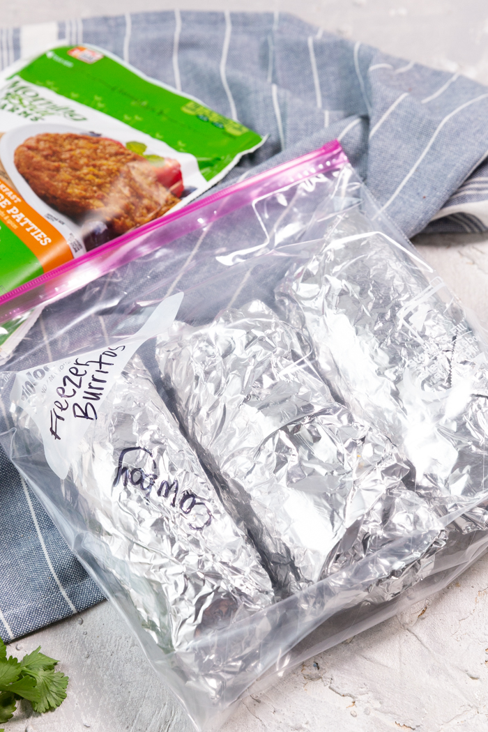 A bag with three freezer burritos and sausage patties in the background