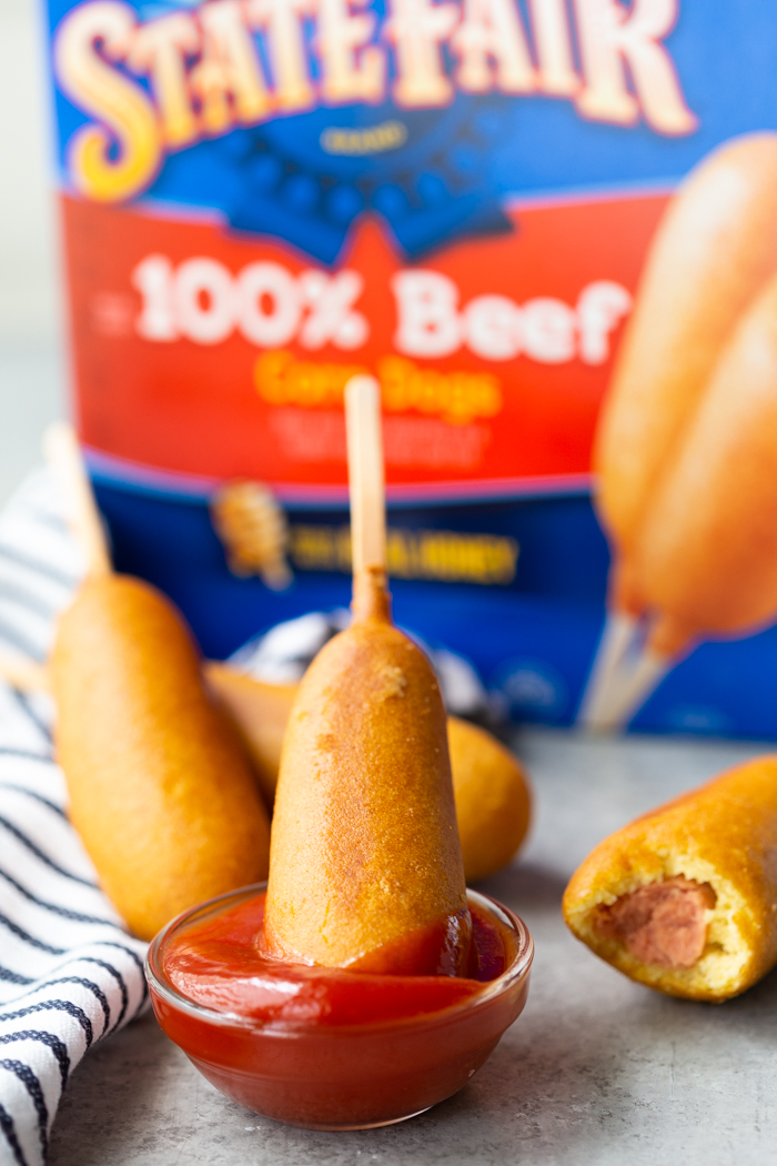 Corn Dog being dipped into a bowl of ketchup