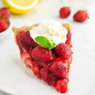 A slice of Strawberry Pie with whipped cream and mint on top