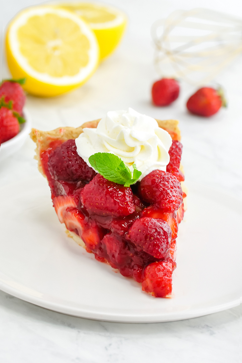 A slice of Strawberry Pie with whipped cream and mint on top