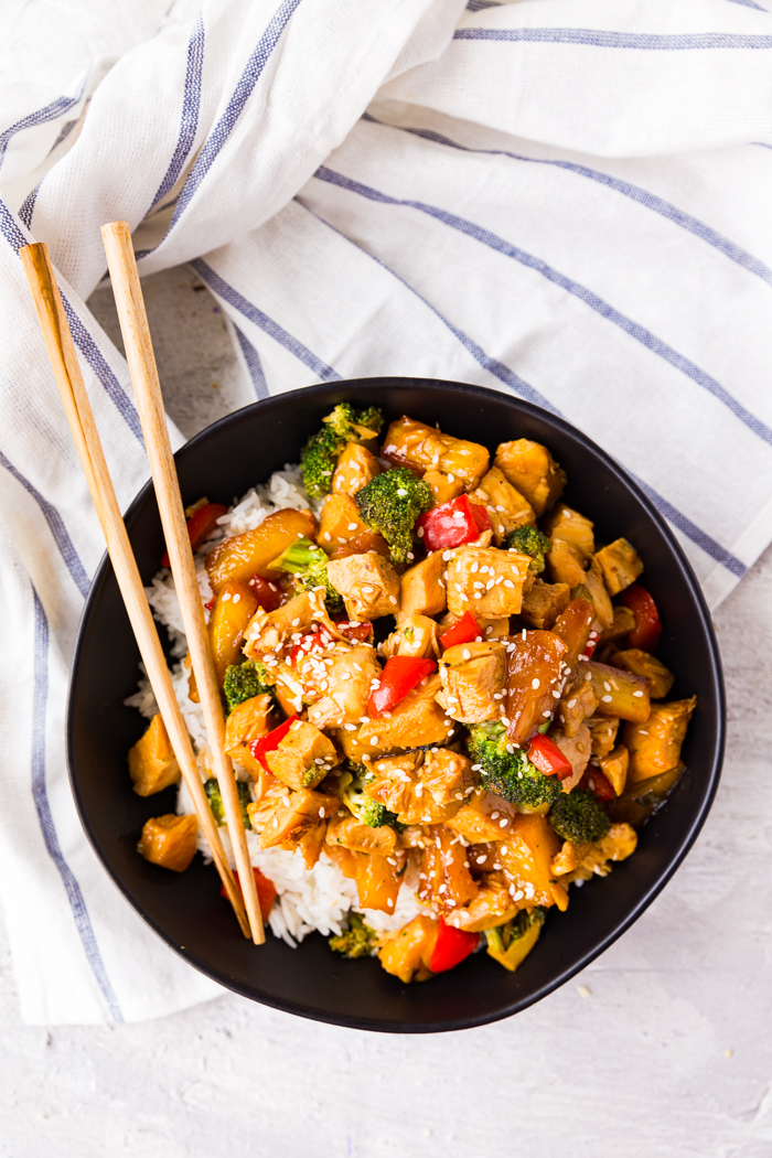 a plate of teriyaki chicken stir fry with chop sticks