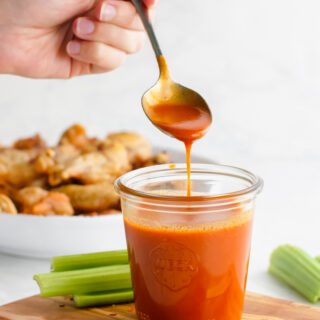 A glass of buffalo sauce with a spoon full