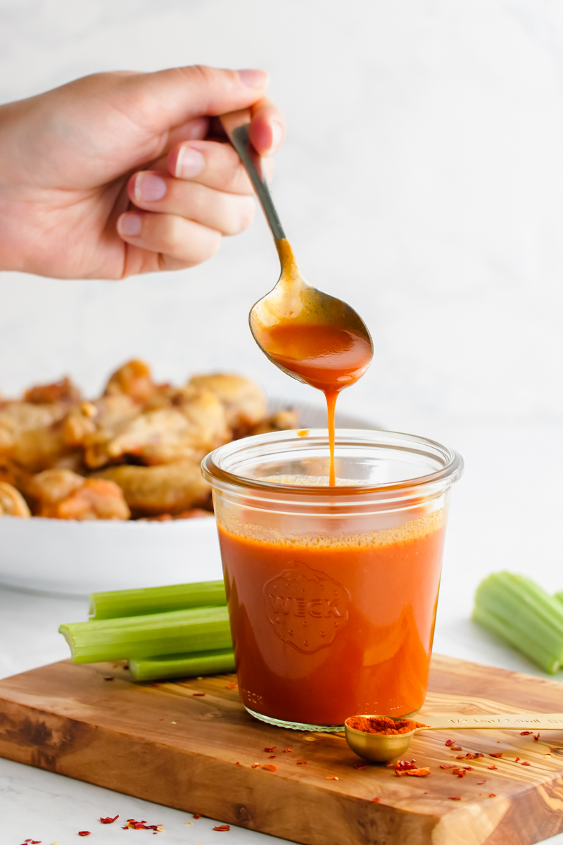 A glass of buffalo sauce with a spoon full