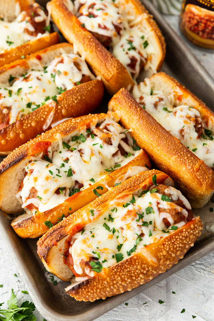 A top down shot of a tray of sloppy joe meatball subs with melted mozzarella cheese. 