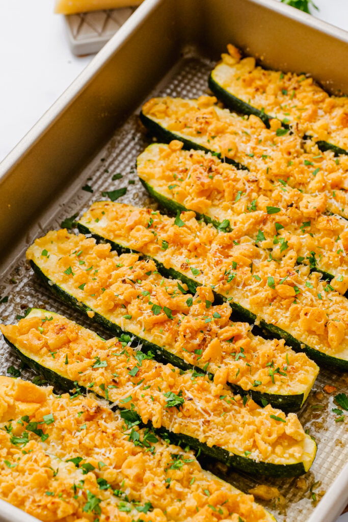 A baking tray with halved and cooked zucchini topped with crumb mixture. 