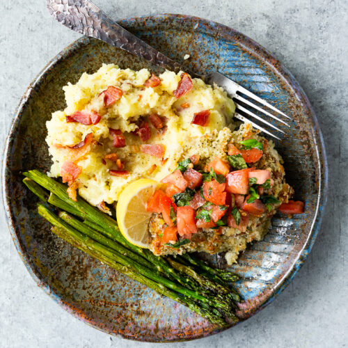 Bruschetta Chicken on a plate with mashed potatoes and asparagus